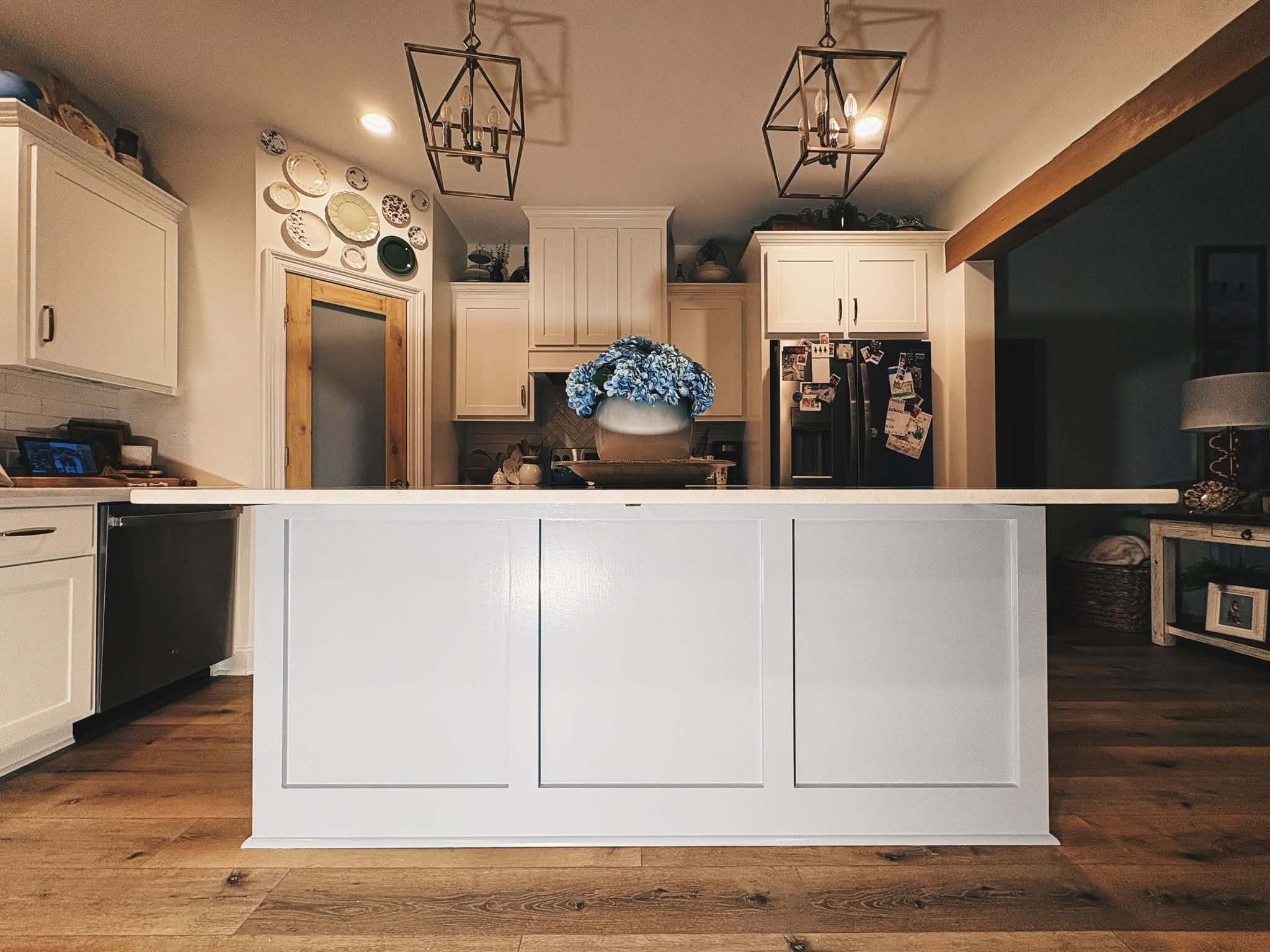 Finished white kitchen island beneath dramatic pendant lighting