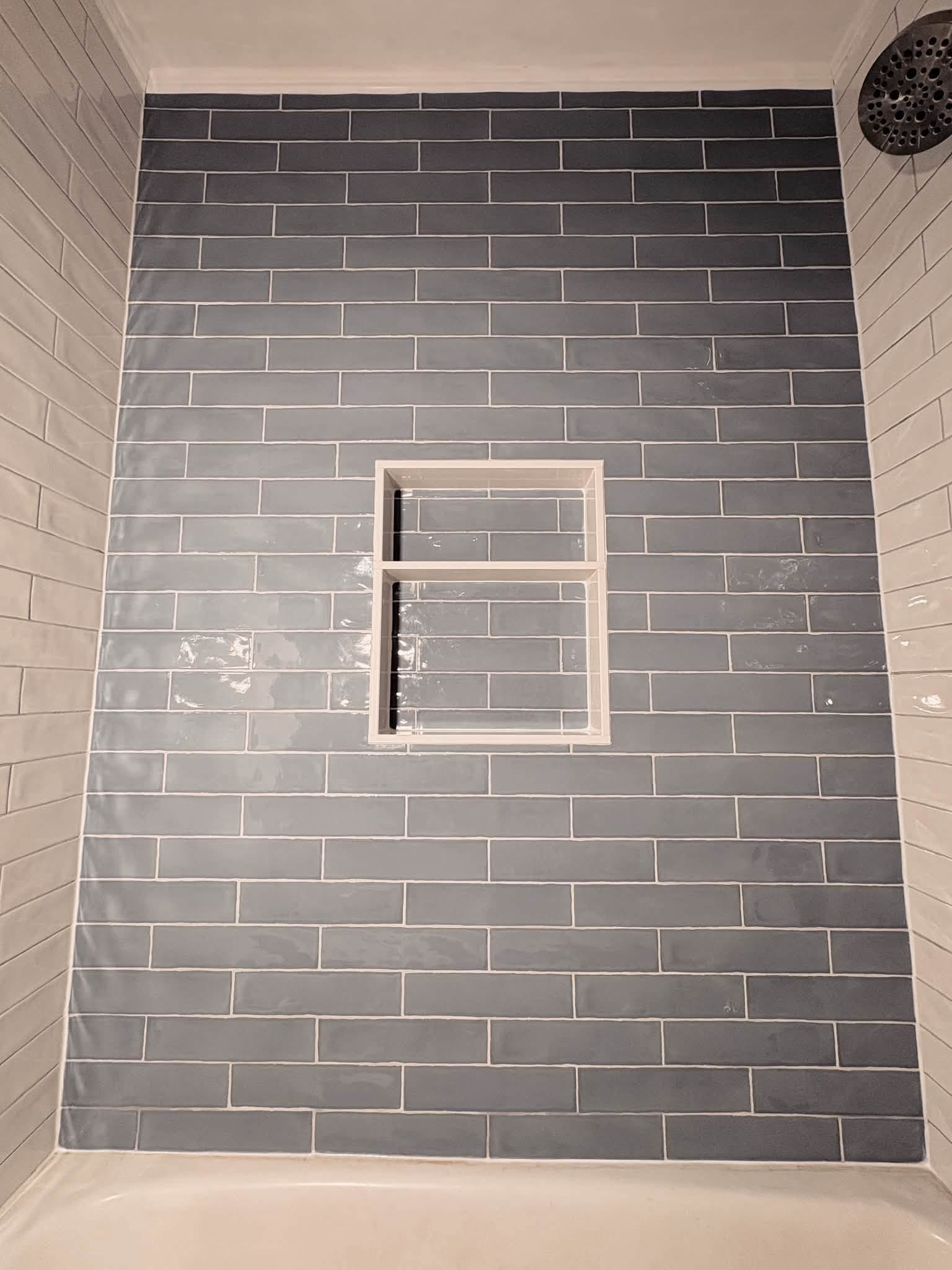 Completed dark tile shower with contrasting white wall