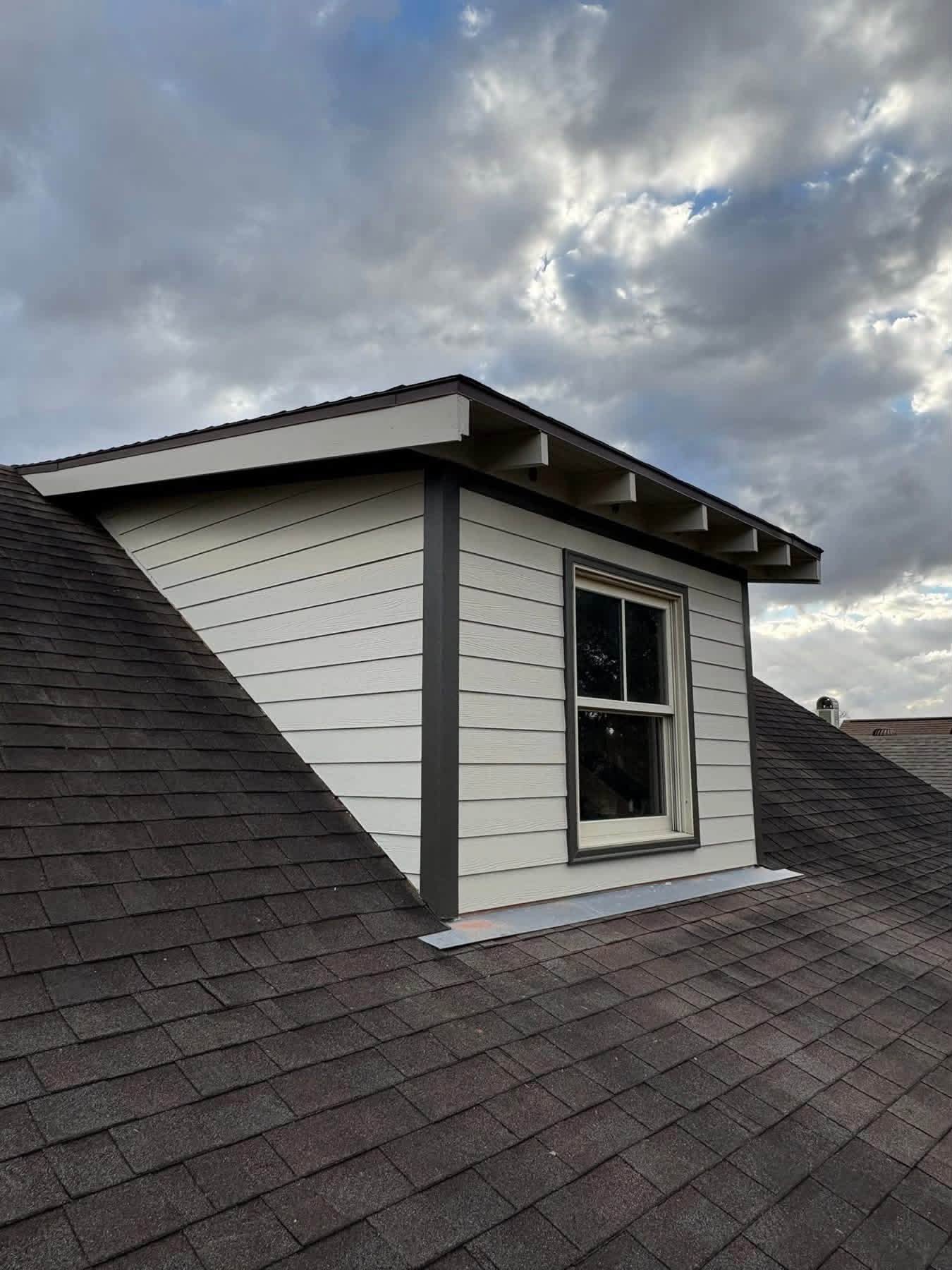 Completed dormer exterior with restored siding, trim, fascia, and soffit